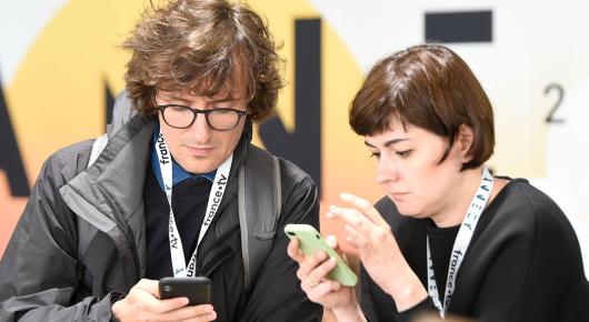 Deux personnes utilisant l'appli mobile du festival. 